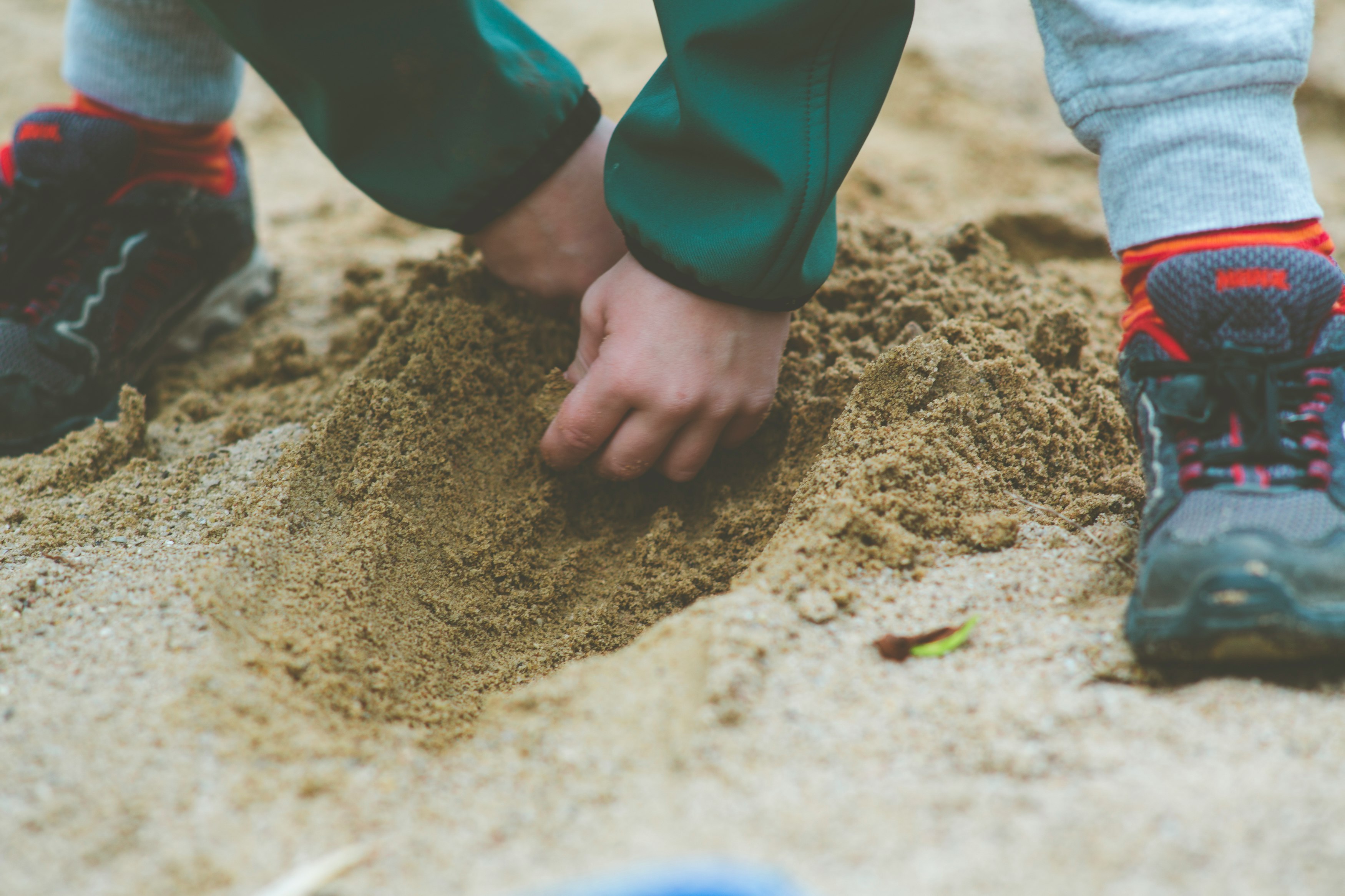 person in blue long sleeve shirt and blue denim jeans standing on brown sand during daytime